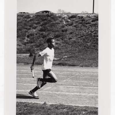 Men's track team member running relay.
