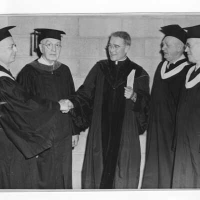 John J. Long, S.J. with four alumni from class of 1899 receiving golden hawk awards as part of 1949 graduation/commencement ceremony. Four black and white prints.