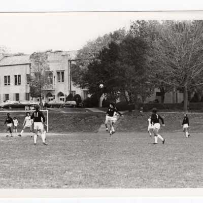 Men's soccer team playing a game on Finnesey Field with Field House in background.