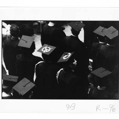 Graduates during 1971 graduation/commencement ceremony with peace symbol on caps.