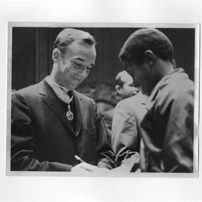 Terrence Toland, S.J., signing autograph for young man during reception for Francois Tombalbaye, President of Chad, after convocation, October 26, 1970.