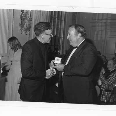 Donald I. MacLean, S.J., presenting award to James J. Gillin, Jr., at alumni awards dinner, c. 1980.