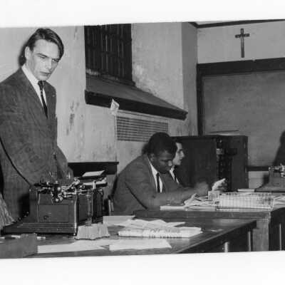 Student members of The Hawk newspaper staff working at desk with manual typewriters.