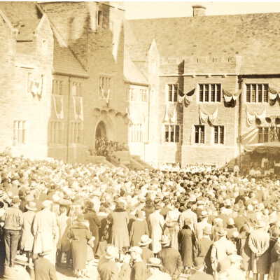 View of crowds in quadrangle during dedication of Barbelin building. Shows loudspeakers and windows draped with banners.