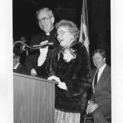 Mary McShain with Nicholas S. Rashford, S.J., at podium, c. 1988.