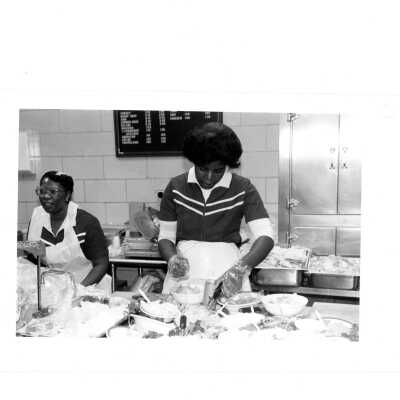 Two employees in Campion cafeteria preparing food.