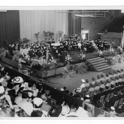 View of 1955 graduation/commencement ceremony in Field House. Two black and white prints.