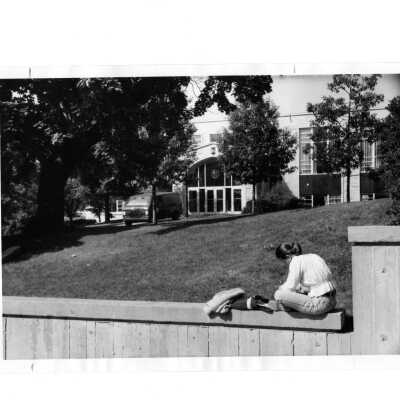 Exterior front view of Campion with student sitting on wall and van.