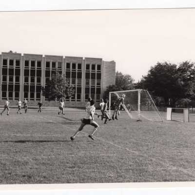 Men's soccer match on Finnesey Field with Post Hall (formerly Villiger) in background.