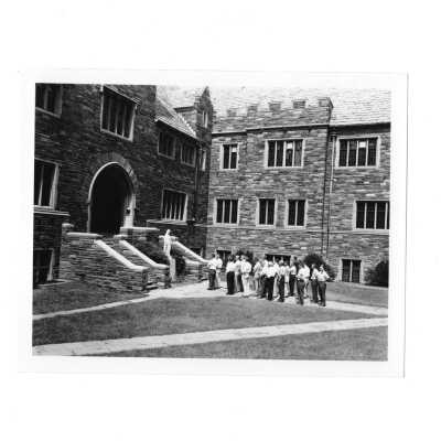 Summer alumni spiritual retreat on SJC campus, c. 1958, with view of attendees standing in Barbelin quadrangle.