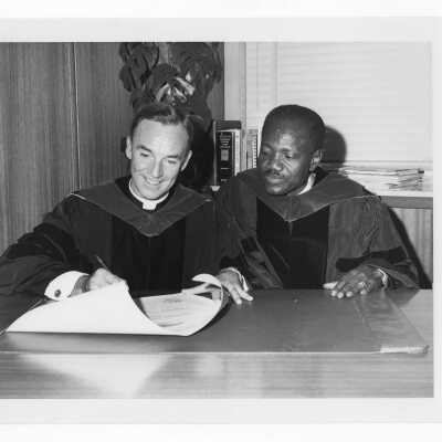 Terrence Toland, S.J., signing honorary degree for the President of Chad, Francois Tombalbaye, during convocation, October 26, 1970. The event was in observance of the twenty-fifth anniversary of the founding of the United Nations.