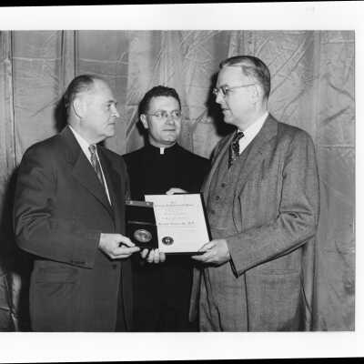 Dr. Joseph Stokes, Jr., showing Shaffrey award medal and certificate to Edward G. Jacklin, S.J., and Myles J. Murphy 1954.
