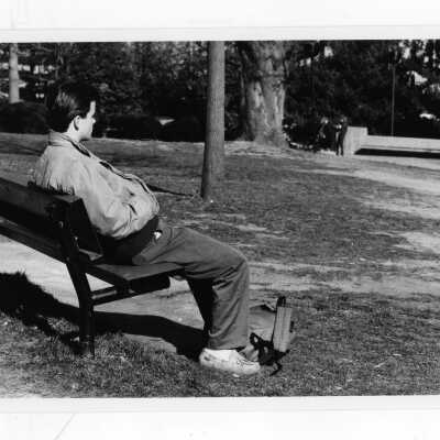 Male student sitting on park bench.