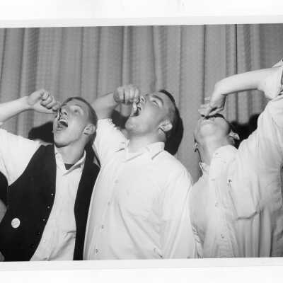 Students, Robert Auve, Thomas Bullock, and Robert Cameron, swallowing goldfish during Junior Week activities.