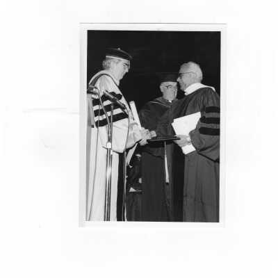 Nicholas S. Rashford, S.J., conferring honorary degree on Cesar Jerez-Garcia, S.J. with William Walsh, S.J. (?) assisting during convocation, March 20, 1990.