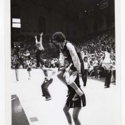 Men and women in two-person pyramids at basketball game.