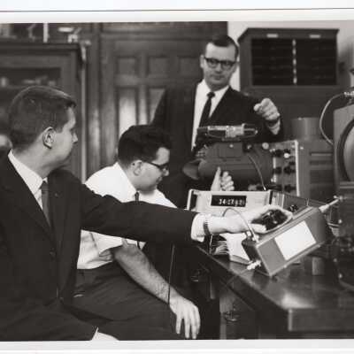 Two physics students working with professor in laboratory, c. 1965.