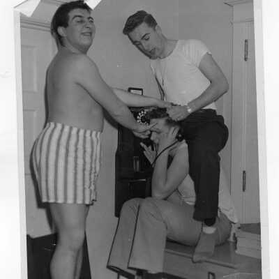 Three students of Barry Hall clowning around near pay telephone.