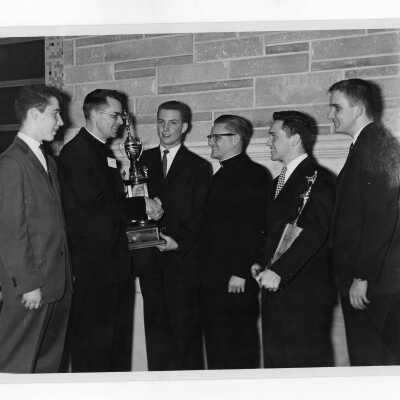 Students from Villiger Debating Society presenting trophy to Jesuit moderator.