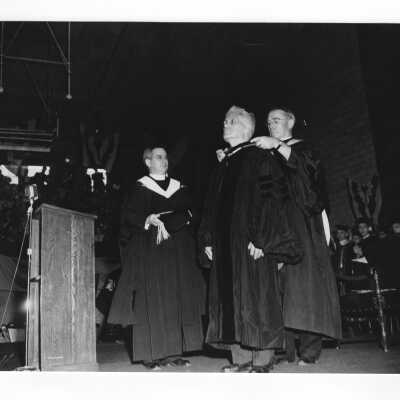 John J. Long, S.J., and Father Drane assisting Thomas K. Quirk, honorary degree recipient, with academic robes during 1950 graduation/commencement ceremony.