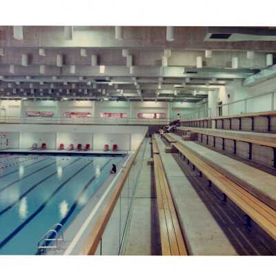 View of swimming pool in Sports Complexwith two students on bleachers.