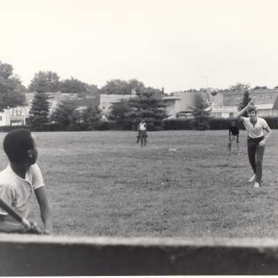 Student playing baseball with neighborhood children on SJU campus as part of community service/outreach program during summer.
