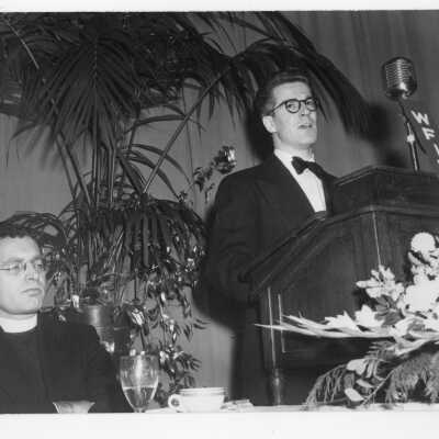 Faculty member, Lawrence J. Bell, delivering speech with Edward G. Jacklin, S.J. nearby during banquet held in Field House as part of centennial anniversary celebration.