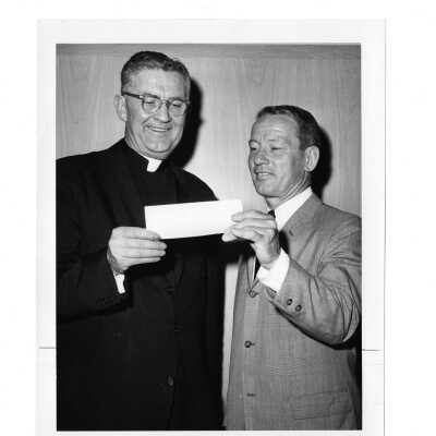 Paul Hagan of class of 1940 presenting check to William F. Maloney, S.J., during alumni reunion held June 5, 1965.
