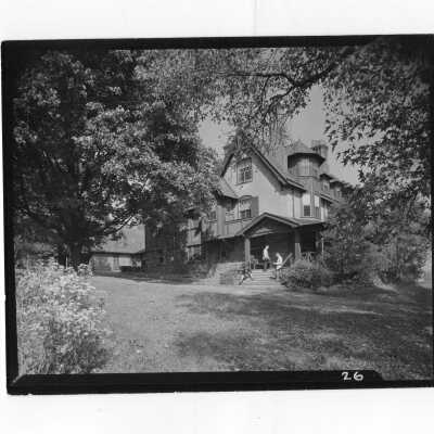 Exterior view of Simpson Hall with two students standing on porch steps.