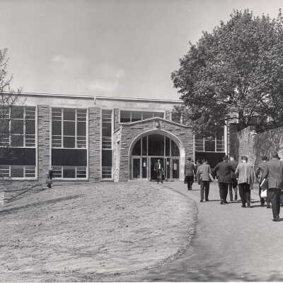 Exterior view of Campion with students walking and stone wall that separated SJC campus from Gest Estate.