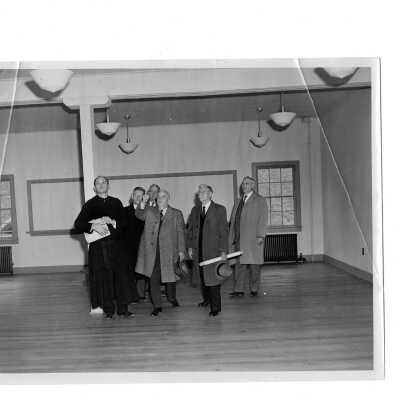 James Buckley, S.J.,(?) Emile G. Perrot, and members of Federal Works Agency inspecting interior of Cardboard College (also known as Barbelin Annex).
