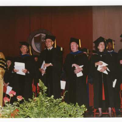 View of Nicholas S. Rashford, S.J., faculty members, and honorary degree recipients on stage during 1990 graduation/commencement.