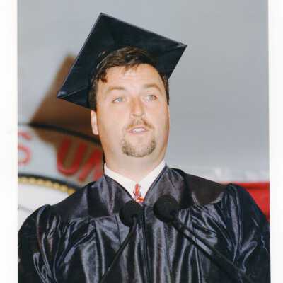 Graduate student, possibly Edward Mancinelli or Joh Versaggi, speaking to audience during 1999 graduation/commencement.