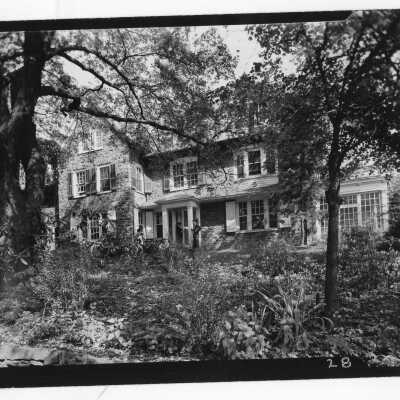 Exterior front view of Greaton Hall with three students standing and talking.