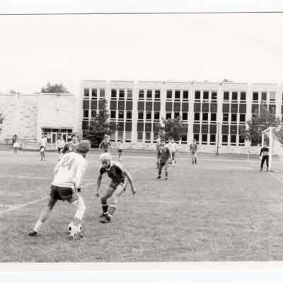 Men's soccer match on Finnesey Field with Post Hall (formerly Villiger) in background.