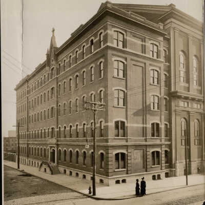 Exterior view of Jesuit faculty residence at Eighteenth and Thompson Streets, Philadelphia, with two women talking on corner.