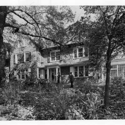 Exterior front view of Greaton Hall with three students standing and talking.