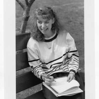 Woman student sitting on park bench studying.