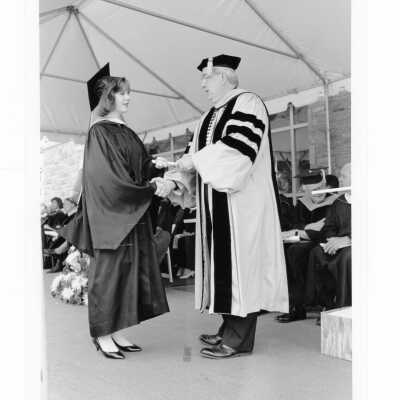 Nicholas S. Rashford, S.J., awarding diploma to graduate.