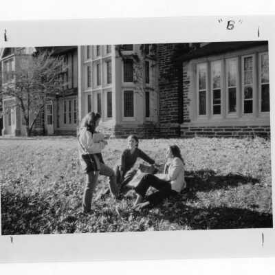 Three women students sitting on lawn outside Saint Mary's Hall.