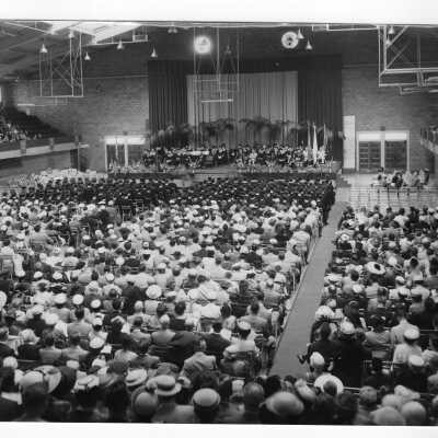 View of 1954 graduation/commencement ceremony in Field House. Two black and white prints.