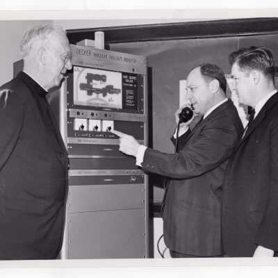 Chemistry professor, Joseph Feighan,working with Decker nuclear fallout monitor, April 17, 1962, with J. Joseph Bluett, S.J., and another individual watching.