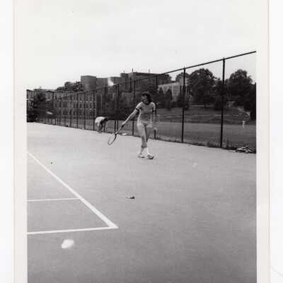 Women's tennis team team member practicing with Finnesey Field, Bellarmine, Science Center, and Drexel Library in background.