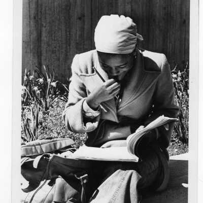 Woman student sitting on wall, studying in early spring with daffodils blooming.