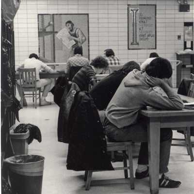 Interior view of students studying at desks in Drexel Library with tile mosaics of Gutenberg, printing press, etc. on back wall.