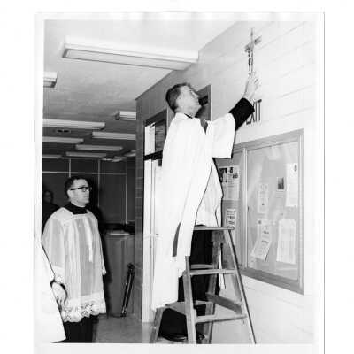 William F. Maloney, S.J. placing cross on wall of Drexel Library in dedication ceremony.