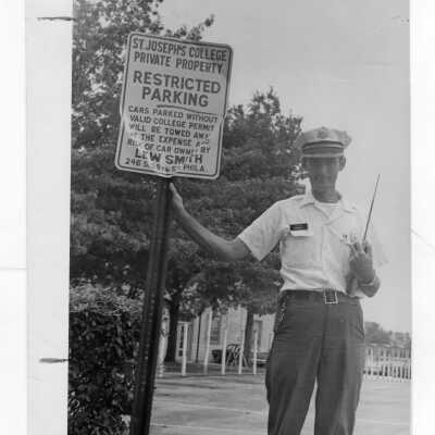 Security guard standing near Saint Joseph's College restricted parking sign.
