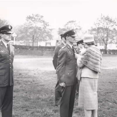 Mrs. Nicholas Kueny, president of Bellarmine Guild, pinning award medal on ROTC cadet during Founders' Day military review on Finnessey Field, May 1, 1961.