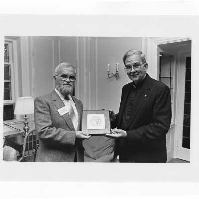 Nicholas S. Rashford, S.J., with Denis Lucey of Cork College in Ireland during his visit to SJU campus. President Rashford is presenting Lucey with a decorative Saint Joseph University plaque.