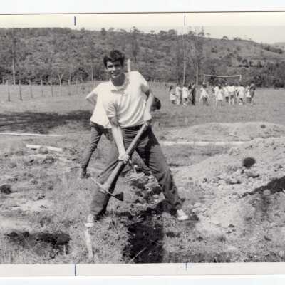 Two students working in field in Colombia with group of children in background during Latin American Studies Institute Summer Service Project, summer 1970.